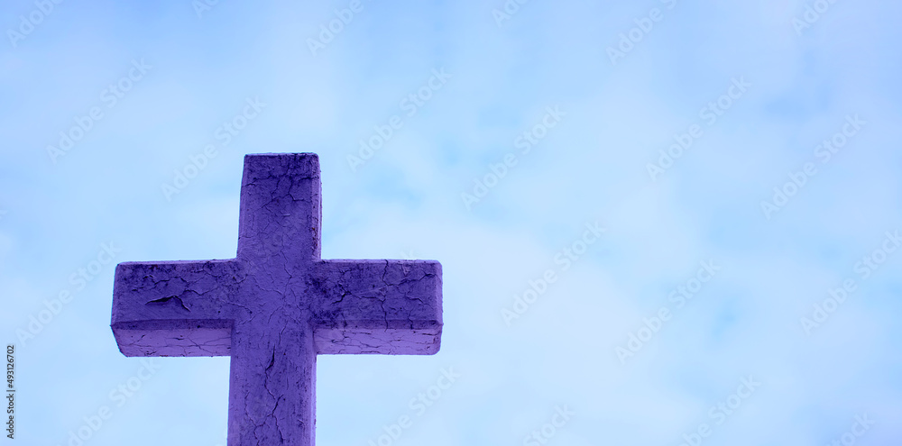 Blue stone cross on light blue sky background