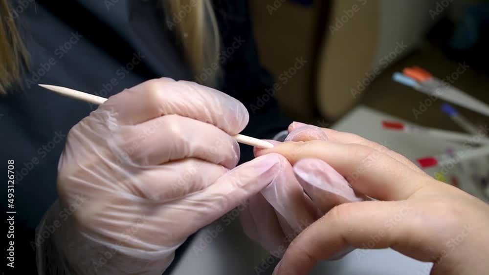 the manicure master protects the nail before the procedure with a wooden stick the manicure master protects the nail before the procedure with a wooden stick