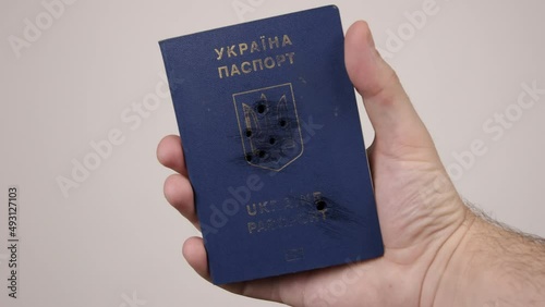 Ukrainian passport held by a man's hand. Holes in the document from gunshots. war in Ukraine. Russian aggression, occupiers photo