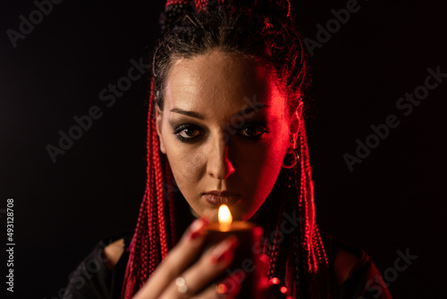 A witch who hypnotizes everyone with the help of a candle. The witch holds a candle close to her face.