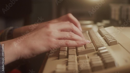 Hands typing on the keyboard of an old  micro computer. Close-up.