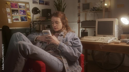 Young girl playing with a 90s portable game console in her bedroom.