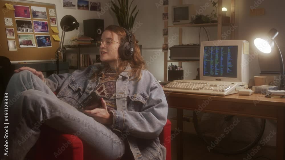 Girl listening to music and singing with a classic walkman player in her bedroom.