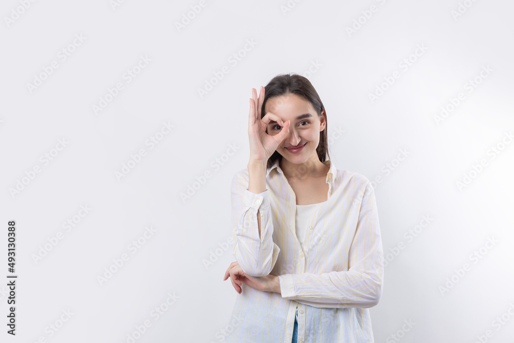 Close up portrait of attractive quirky young woman making binoculars with hands showing ok gesture on white studio background. Close up portrait of attractive quirky young woman making binoculars with hands showing ok gesture on white studio background.