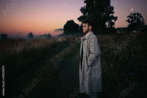 lonely man in a gray raincoat in a field in the morning at dawn in a foggy field, reflections on life existential crisis. © velimir