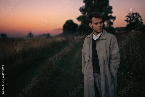 lonely man in a gray raincoat in a field in the morning at dawn in a foggy field, reflections on life existential crisis.