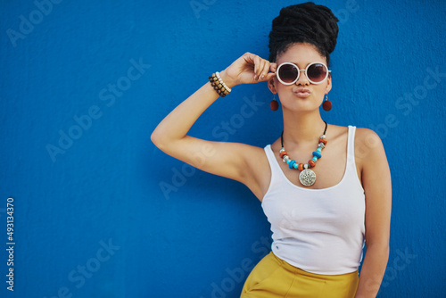 When your pout is on point. Shot of an attractive young woman wearing funky sunglasses against a blue background.