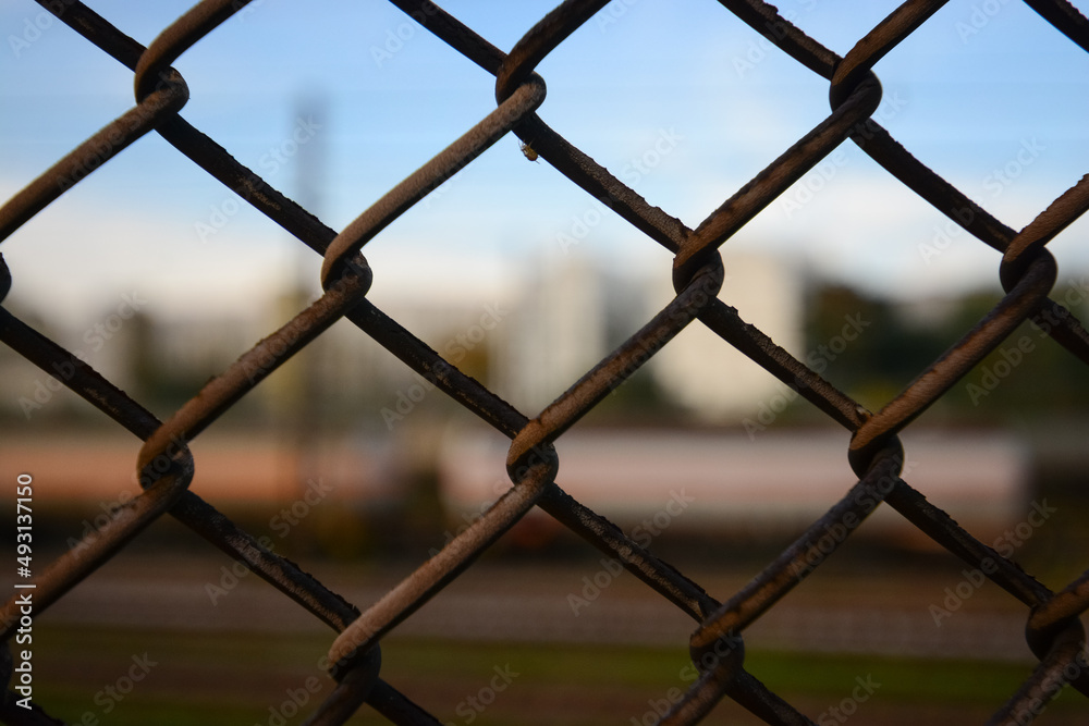 close-up of ice rusty fences with blurred background in which a train can be guessed