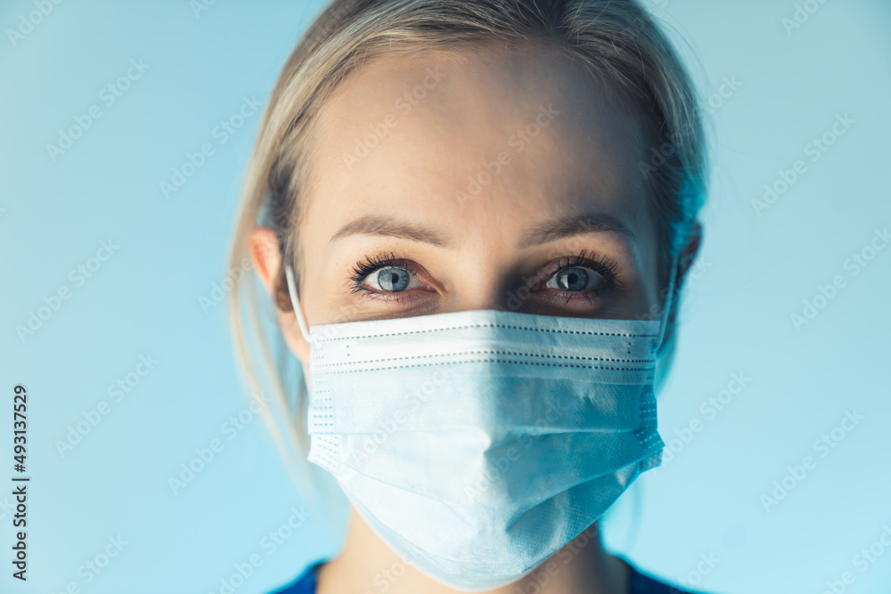 Confident caucasian nurse lady wearing professional mask, educates about safety. close up studio shot, blue background. High quality photo Confident caucasian nurse lady wearing professional mask, educates about safety. close up studio shot, blue background. High quality photo