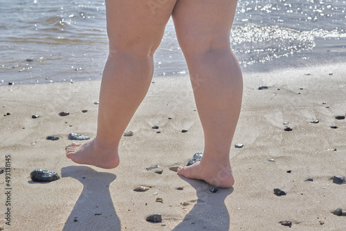Legs of a woman walking on the shore of the beach 