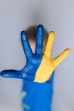 The flag of Ukraine is drawn on the palm of the child , stop