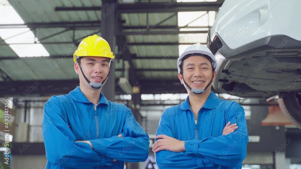Portrait of Asian two handsome automotive mechanic men stand in garagE Portrait of Asian two handsome automotive mechanic men stand in garagE