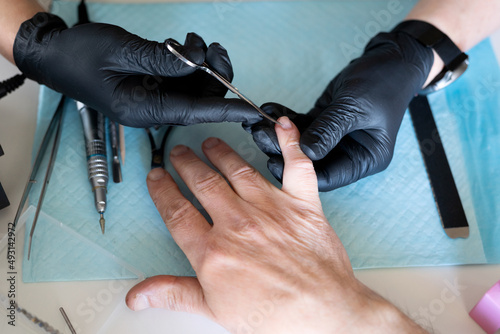 Manicurist is cutting cuticle on man's hand