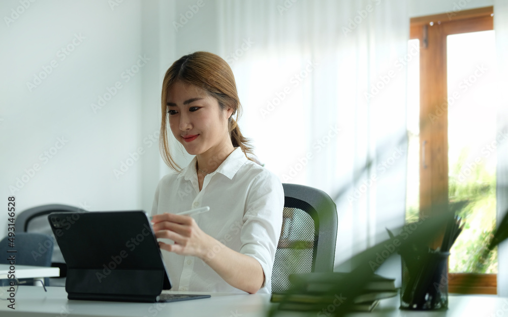 Pretty young female office worker using computer tablet at modern workplace. Pretty young female office worker using computer tablet at modern workplace.