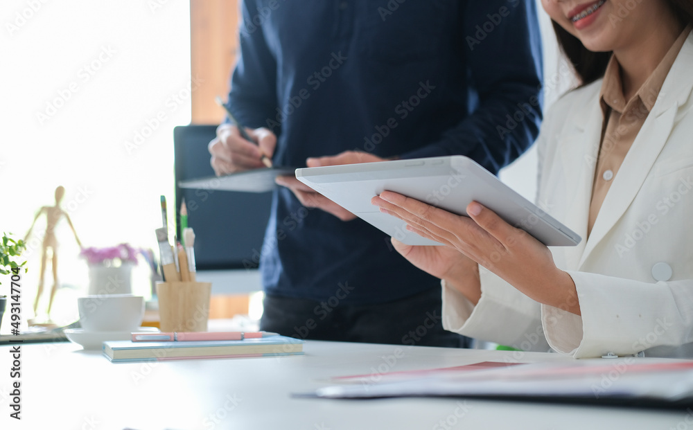 Two businesspeople analysing financial data on digital tablet at modern workplace. Two businesspeople analysing financial data on digital tablet at modern workplace.