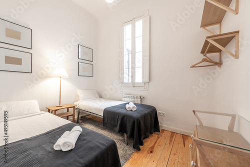 Bedroom with double beds  gray carpet  shared wooden nightstand  red parquet floor  wooden shelves and matching dresser and gray blanket with rolled towels