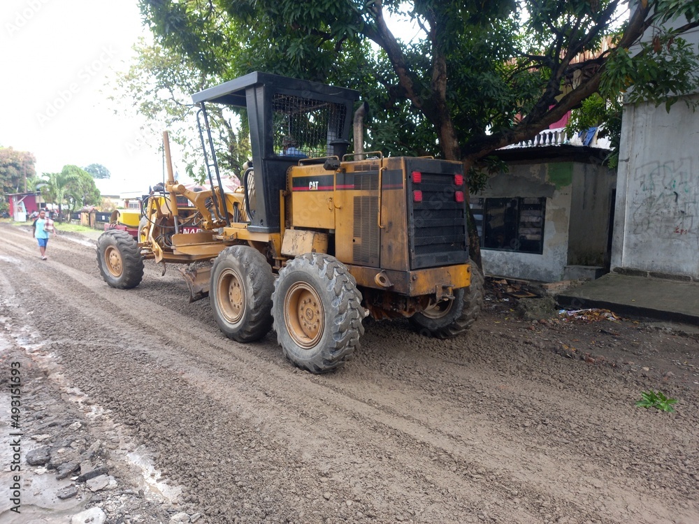 Medan, Indonesia - February 07, 2022: Motor grader is leveling the road for paving