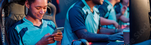 Cute female cybersport gamer sitting in gaming chair and playing mobile game on cellphone in computer club