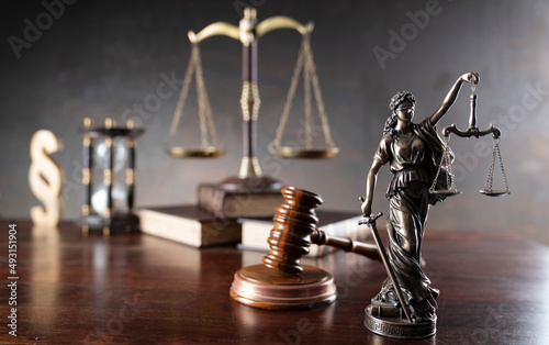 Law and justice concept. War crimes. Gavel, Themis sculpture, law code and scale in lawyers office. Gray background.