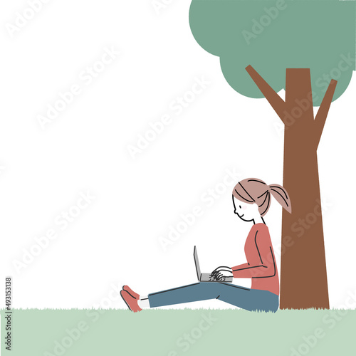 芝生の上でパソコンを操作する女性