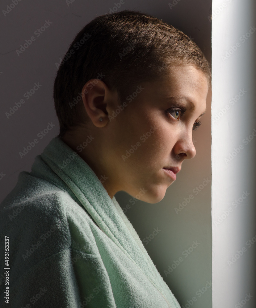 Fototapeta premium Young cancer patient standing in front of hospital window