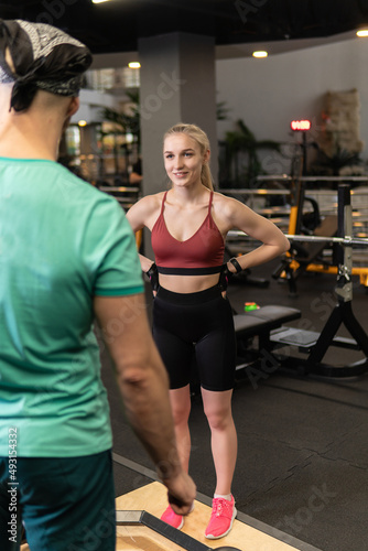 Instructor led training helps a beautiful client to perform exercises in a fitness club, the concept of playing sports with a professional gym leisure lifestyle mature modern, for personal retired for