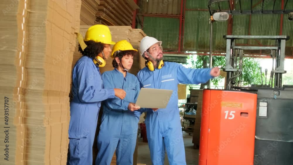 Industry factory workers team in safety uniform and hard hat inspect storage by laptop, stock order at warehouse, management piles of stacking cardboard with a forklift, manufacture product logistic. Industry factory workers team in safety uniform and hard hat inspect storage by laptop, stock order at warehouse, management piles of stacking cardboard with a forklift, manufacture product logistic.