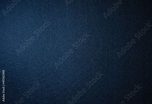 Photo of the texture of felt fabric in dark blue.Pure blue background for the inscription. Soft dark background. Fabric backing.
