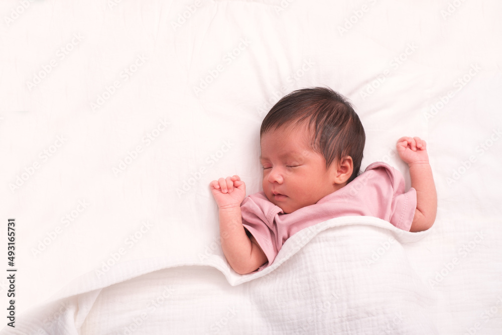 Top view portrait of cute adorable baby girl on white bed in bedroom. Newborn child relaxing and smiling in the bed in children nursery. Family morning at home Top view portrait of cute adorable baby girl on white bed in bedroom. Newborn child relaxing and smiling in the bed in children nursery. Family morning at home