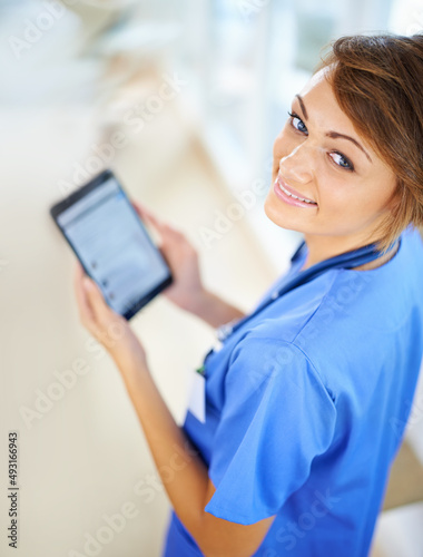 Technology helps me keep track of my patients progress. Portrait of an attractive young doctor in scrubs holding a digital tablet.