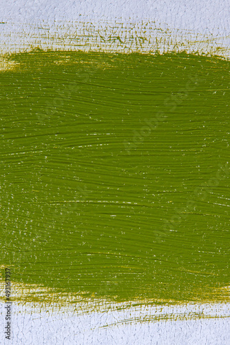 wide brush stroke with saturated bright light olive-green paint on a white background, close up