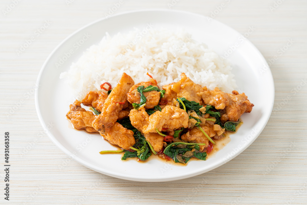 stir-fried fried fish with basil and chili in thai style topped on rice stir-fried fried fish with basil and chili in thai style topped on rice