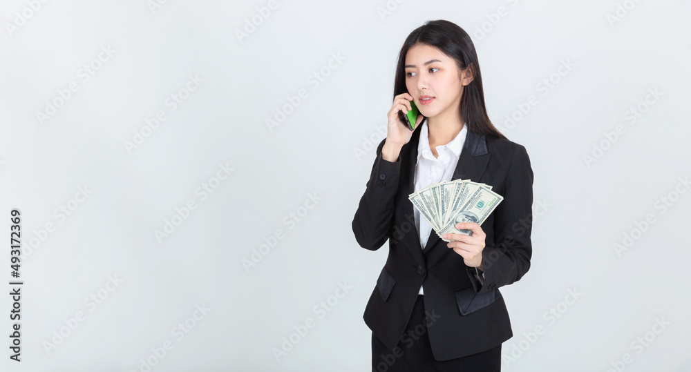 business asian woman wearing office clothing successful hold smart phone mobile and US dollars money in hand feeling happy and smile, bankruptcy economic financial concept. business asian woman wearing office clothing successful hold smart phone mobile and US dollars money in hand feeling happy and smile, bankruptcy economic financial concept.