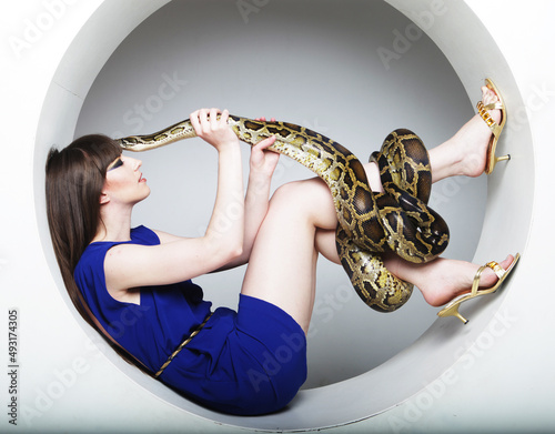 Young woman with long hair wearing blue dress holding a Python.