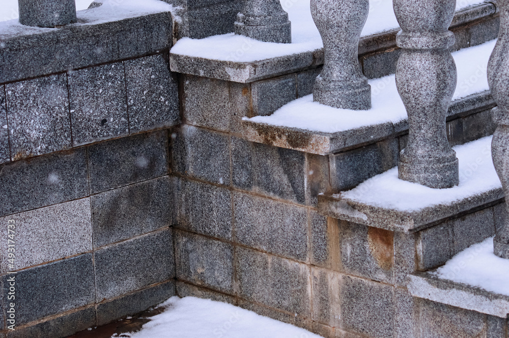 Balustrade of the rotunda under the snow. Gray granite exterior details during a snowfall. Fragment of a city landmark in winter. Balustrade of the rotunda under the snow. Gray granite exterior details during a snowfall. Fragment of a city landmark in winter.