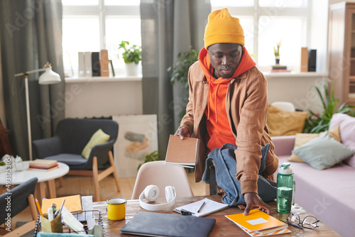фотографія Horizontal shot of modern African American college student standing at desk gett