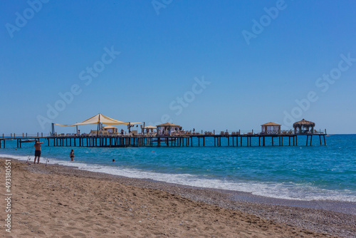 Pier and beach on a clear day with blue sea © Ilia Grechko