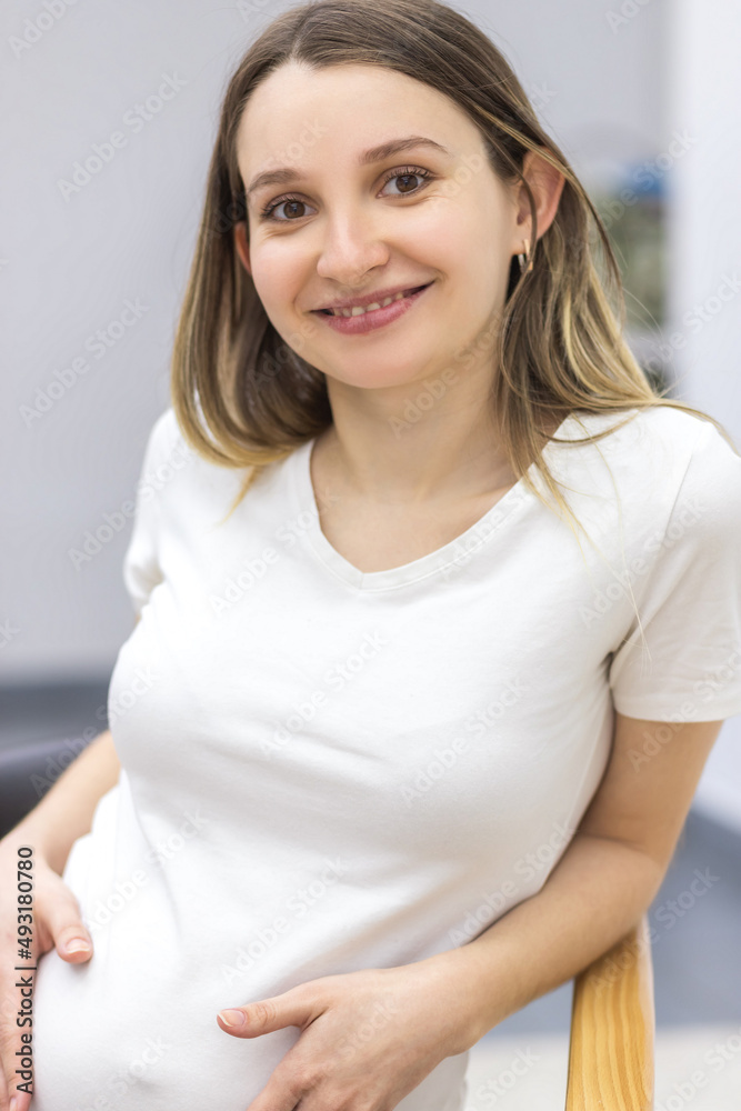 Photo of pregnant woman looking at camera and touching her stomach. Photo of pregnant woman looking at camera and touching her stomach.