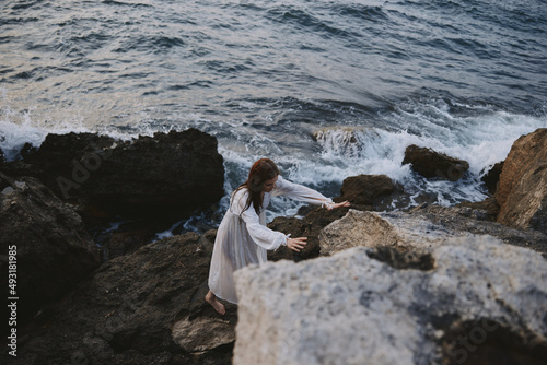 Woman in white dress with wet hair near the ocean waves nature cliff