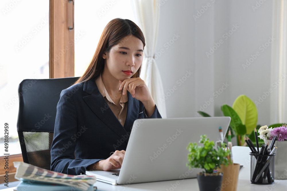 Young female designer sitting at graphic studio in front of laptop computer while working online. Young female designer sitting at graphic studio in front of laptop computer while working online.