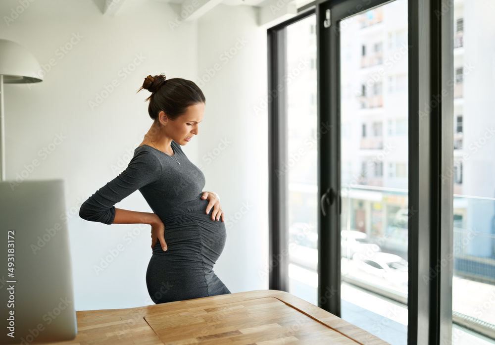 Any day now.... Shot of a pregnant businesswoman standing in her office holding her stomach. Any day now.... Shot of a pregnant businesswoman standing in her office holding her stomach.