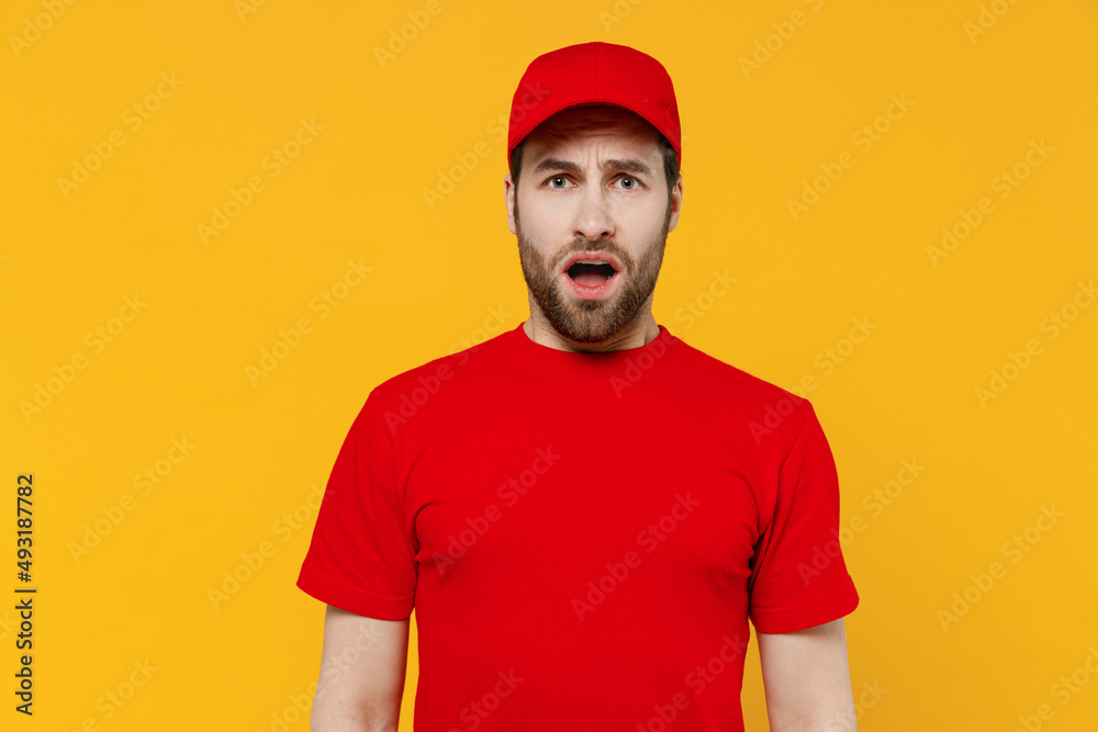 Professional displeased sad dissatisifed delivery guy employee man in red cap T-shirt uniform workwear work as dealer courier look camera isolated on plain yellow background studio. Service concept. Professional displeased sad dissatisifed delivery guy employee man in red cap T-shirt uniform workwear work as dealer courier look camera isolated on plain yellow background studio. Service concept.