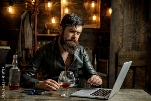 Bearded business man with glass of whiskey. Stressed from hard work.