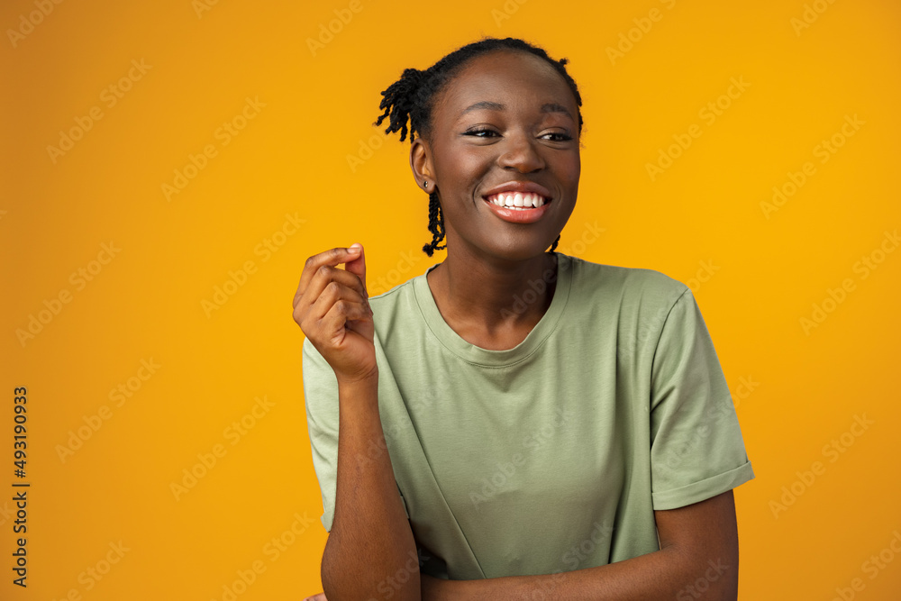 Happy african american woman looking surprised in yellow studio Happy african american woman looking surprised in yellow studio