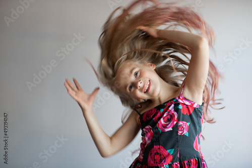 Teen girl with long hair flying in air, over studio grey background