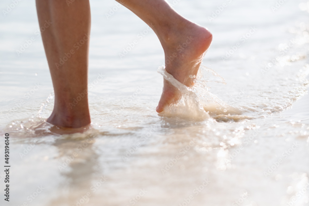 Closeup image of woman with barefoot while walking on the white beach and the sea Closeup image of woman with barefoot while walking on the white beach and the sea