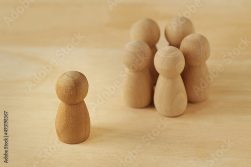 Wooden pawns representing group of people in circle and person alone - Concept of racism, social exclusion and isolation photo