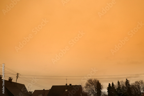 Eine Wolke aus Saharastaub Saharasand verfärbt den Himmel gelb über den Dächern von Meitingen im Landkreis Augsburg in Süddeutschland, ein seltenes Wetterphänomen photo