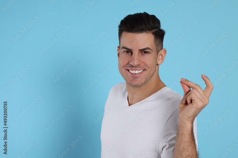 Handsome man snapping fingers on light blue background. Space for text Handsome man snapping fingers on light blue background. Space for text