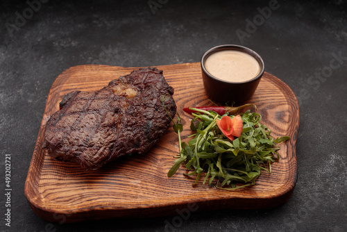 Grilled steak with sauce and herbs, on a wooden board